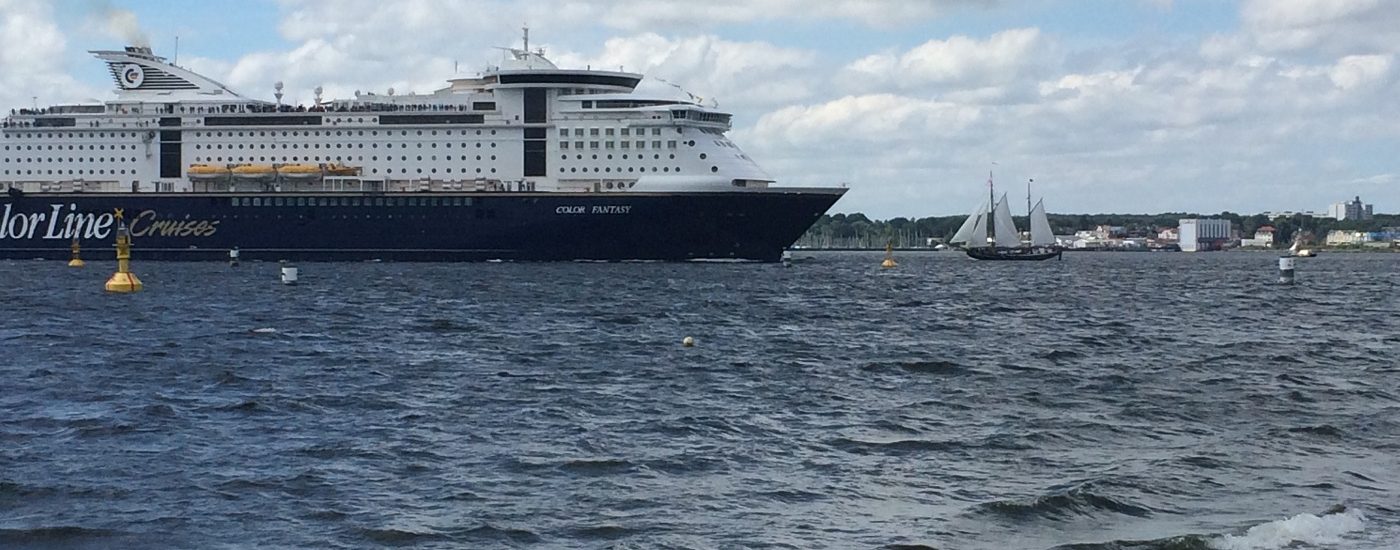 Auf dem Foto ist ein Fährschiff zu sehen und ein Segelschiff auf der Ostsee zu sehen