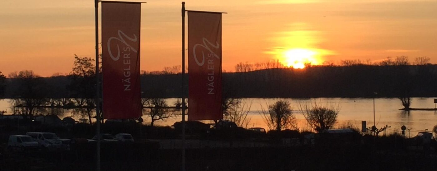 Fahnen vom Hotel Naegler's mit Blick auf den Rhein im Sonnenaufgang